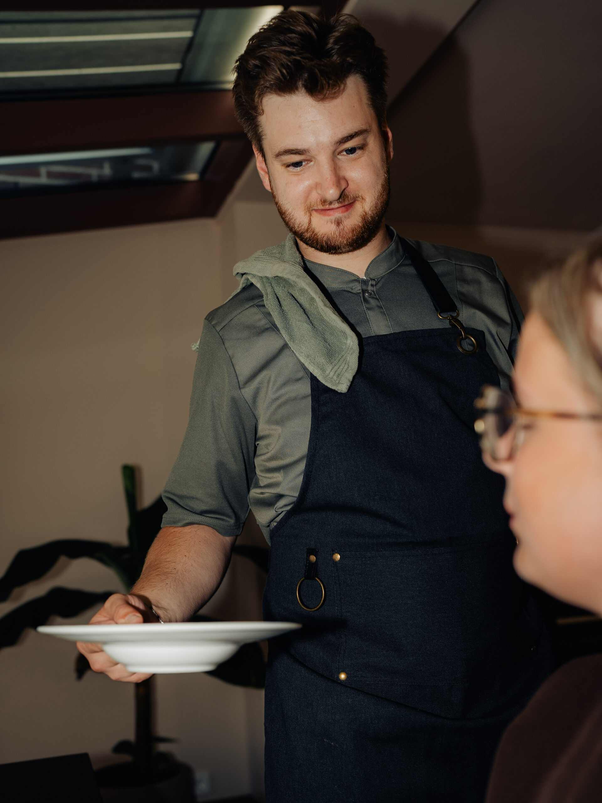 Noah serveert lachend een bord aan tafel